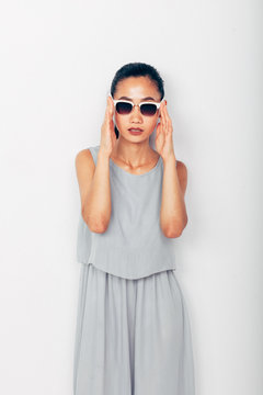 Young beautiful Asian woman in summer grey clothes and sunglasses