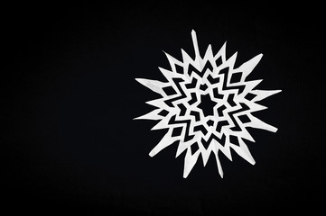 snowflake cut from paper on black background