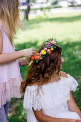 Naklejka premium Putting a flower wreath to the hairs of young beautiful model.