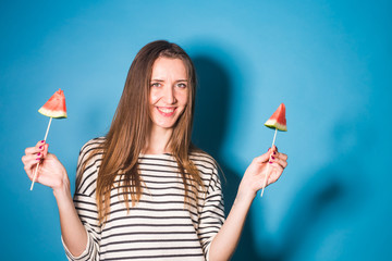 Girl holding a pieces of watermelon on a stick. Summer, holiday, fruit and people concept