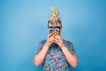 Funny man hold pineapple with sunglasses on blue background