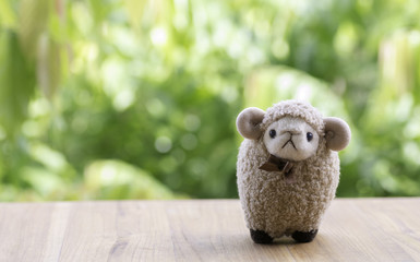 Brown sheep doll Stand on a wooden floor, the background blurred.