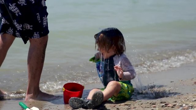Father And Son Play At Beach, Father Pours A Bucket Of Water On His Son's Head, Funny And Cute, Slow Motion