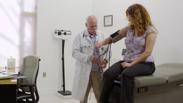 Elderly doctor checking patients blood pressure