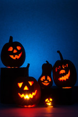 Five Halloween pumpkins, merry faces on a blue background.