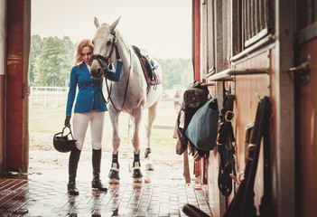 Obraz premium Middle-aged woman with her horse in a stall