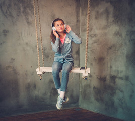 Little girl listening music on a swings