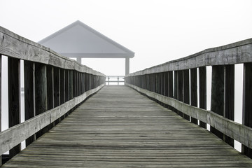 Fototapeta premium Pier leading to a fishing pavilion fading into a mist