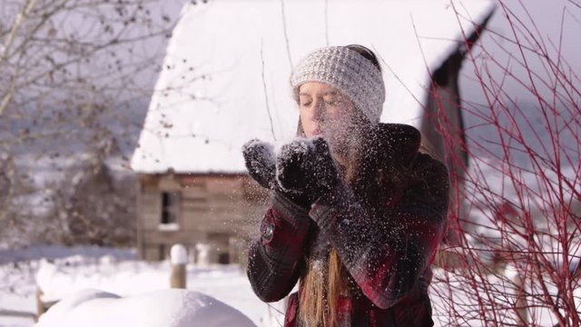 Slow motion young woman blowing and playing with snow