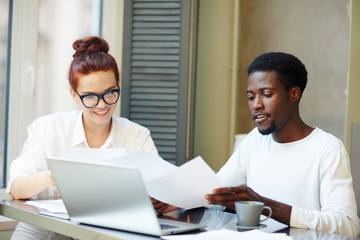 Young man and woman looking through financial papers while working at home office