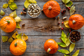 Pumpkin harvest. Pumpkins near nuts and autumn leaves on wooden background top view copyspace