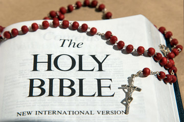 Wooden rosary on the Bible in the aureole of the divine of Divine Rays