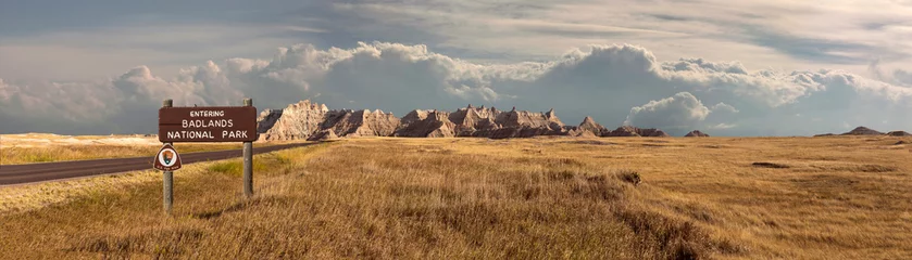 Fototapete Naturpark Weites Landschaftspanorama des Badlands-Nationalparks mit Beschilderung, die in Gewitterwolken eindringt