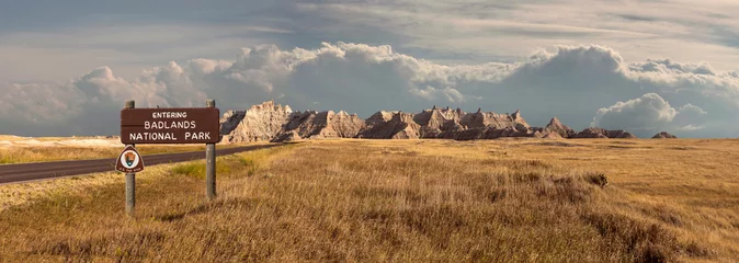 Fototapete Naturpark Landschaftspanorama von Badlands Rocky Mountain Range, Wolken und Grünland mit Schild