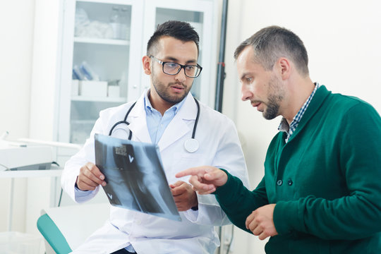 Doctor and patient pointing at x-ray image of joint during medical consultation