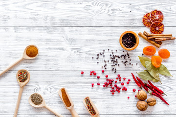 Variety of spices and dry herbs in bowls on light wooden kitchen table background top view mock-up