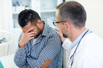 Worried patient hiding his face while doctor reassuring him