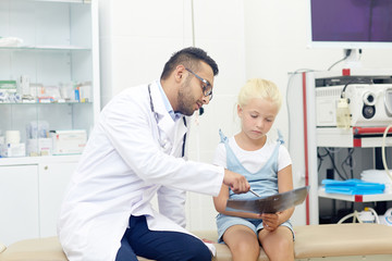 Fototapeta premium Little girl looking at x-ray image while doctor explaining it