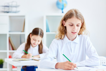 Little learners drawing with pencils or making notes during exam