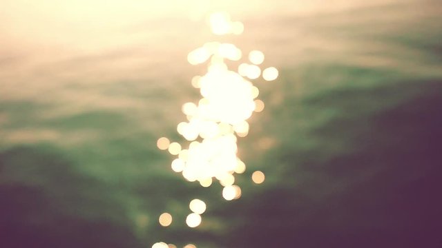 Glistening and shimmering ocean surface at sunset or twilight. Beautiful bokeh of dancing sun reflections on water in slow motion. 1920x1080