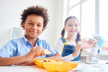 Modern schoolkids eating snacks from containers at break