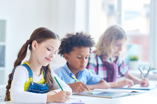 Group of clever schoolkids carrying out task or preparing for lesson