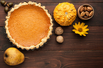 Obraz na płótnie Canvas pumpkin homemade pie at wooden background arranged with food ingredients top view