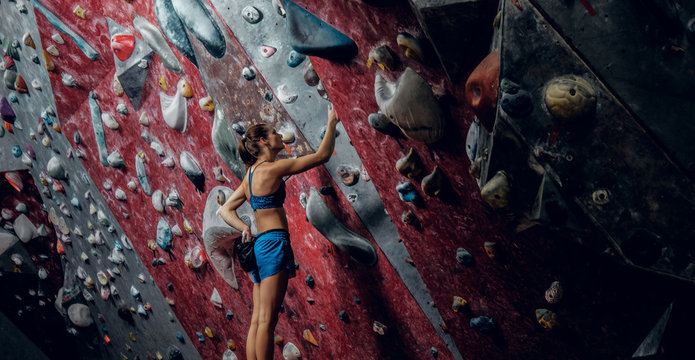Free climber female bouldering indoors.