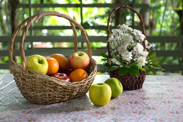 Fruits and Flowers in the rattan baskets on the table in green garden