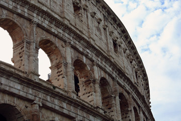 Fototapeta premium Closeup portrait of Coliseum building old wall with arch in Rome, Italy under blue sky in summer day