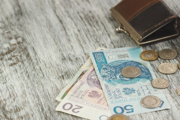 Polish zloty with little wallet on the old wooden background