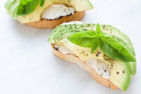 Bruschetta with cream cheese, avocado and basil. Close up