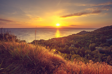 Majestic nature landscape with sunset sky, river and forest. Exploring beauty world: Ukraine, Europe. Travel, hiking, holidays, recreation. Travel background. Autumn season. Orange toning effect