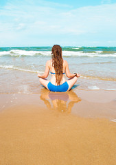 Fototapeta na wymiar Young woman practicing yoga by the sea