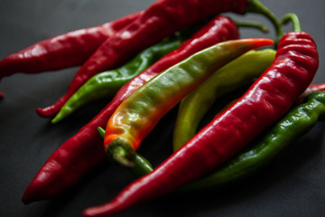 Red and green chili on black background
