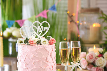 Beautiful cake for lesbian wedding decorated with flowers in the room