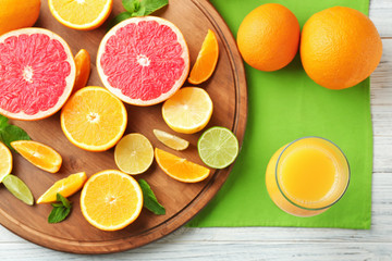 Glass of fresh orange juice and citrus fruits on table