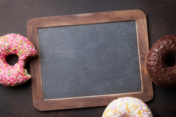 Chalkboard and colorful donuts on stone table
