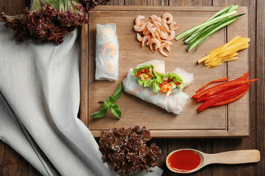 Composition with fresh spring rolls in rice paper and ingredients on table