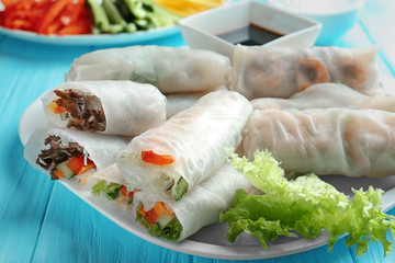 Plate with fresh spring rolls in rice paper on table