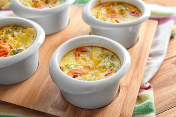 Ramekins with broccoli casserole on wooden stand