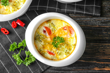 Ramekin with tasty broccoli casserole on wooden table