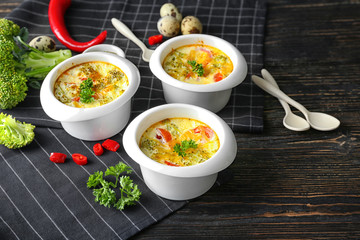 Ramekins with tasty broccoli casserole on wooden table
