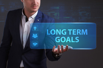 Business, Technology, Internet and network concept. Young businessman working on a virtual screen of the future and sees the inscription: Long term goals