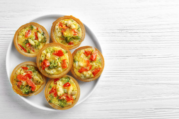 Plate with broccoli quiche tartlets on table