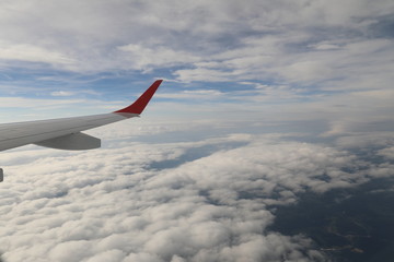 Fototapeta na wymiar Clouds and earth below the wing of an airplane.