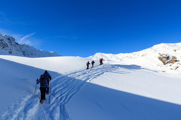 Fototapeta na wymiar Group of people hiking on snowshoes and mountain snow panorama with blue sky in Stubai Alps, Austria