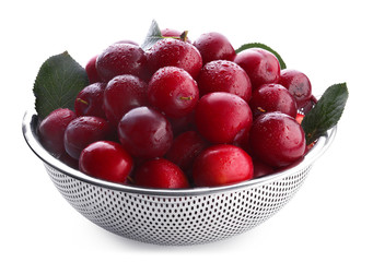 Ripe plums in colander on white background