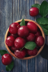 Bowl with ripe fresh plums on wooden table