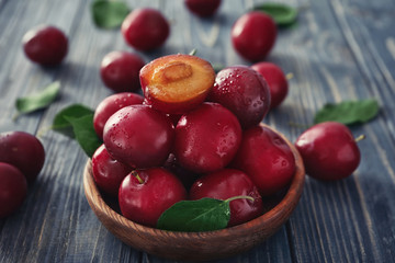 Fototapeta na wymiar Bowl with ripe fresh plums on wooden table